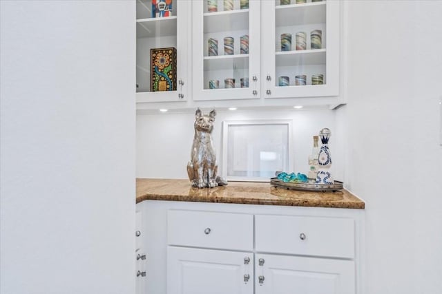 bar with dark stone counters and white cabinets