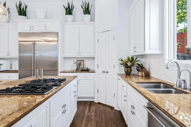 kitchen featuring appliances with stainless steel finishes, tasteful backsplash, sink, white cabinets, and dark wood-type flooring