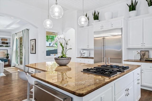 kitchen featuring dark stone countertops, a kitchen island, white cabinets, and appliances with stainless steel finishes