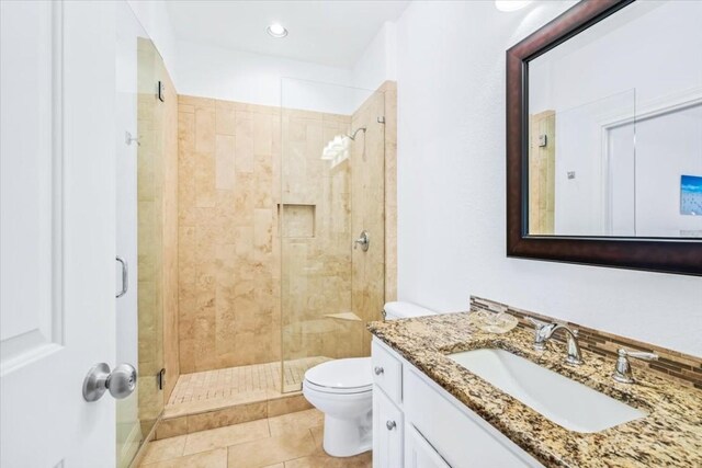 bathroom featuring vanity, tile patterned flooring, toilet, and walk in shower