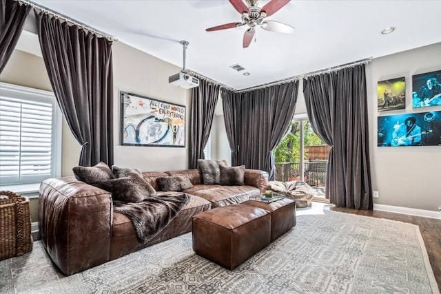 cinema with light hardwood / wood-style floors and ceiling fan