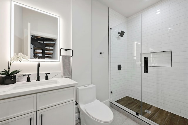 bathroom featuring a shower with door, vanity, and toilet