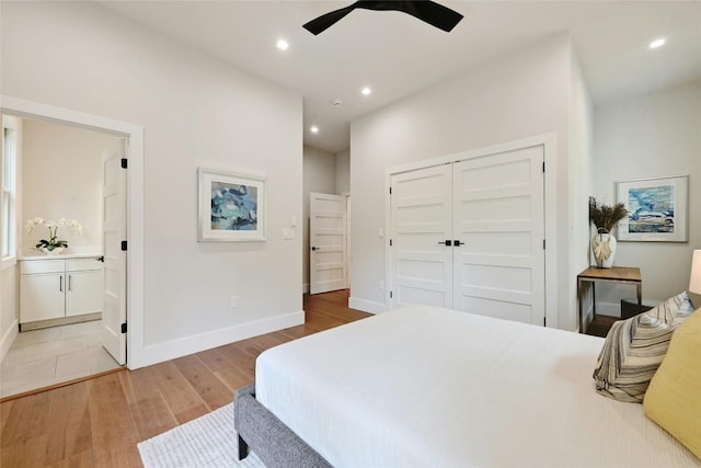 bedroom featuring ceiling fan, connected bathroom, light wood-type flooring, and a closet