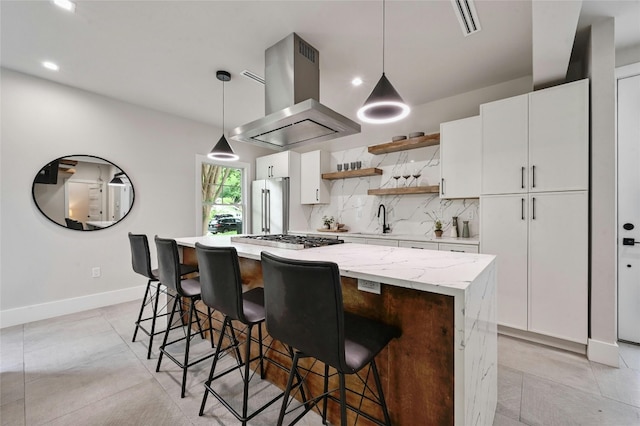 kitchen with pendant lighting, island range hood, white cabinets, and appliances with stainless steel finishes