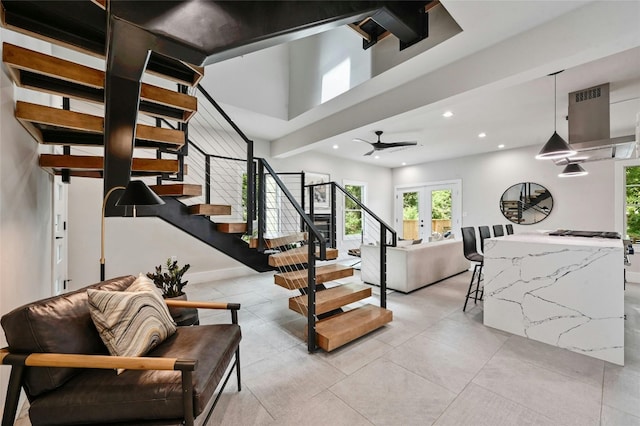 stairs with a towering ceiling, tile patterned floors, french doors, and ceiling fan