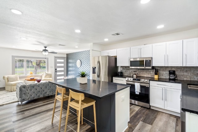 kitchen with stainless steel appliances, a center island, white cabinets, and a kitchen breakfast bar