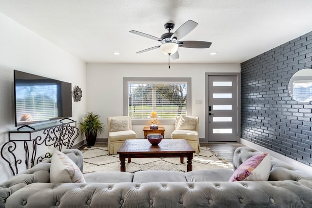 living room with ceiling fan, brick wall, and light hardwood / wood-style flooring