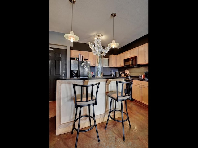 kitchen featuring a kitchen bar, decorative light fixtures, light brown cabinets, and black appliances