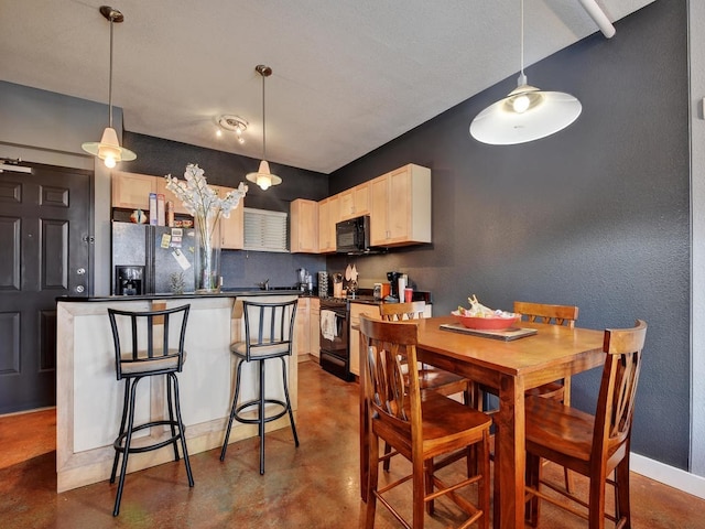 kitchen with pendant lighting, concrete floors, light brown cabinetry, and black appliances