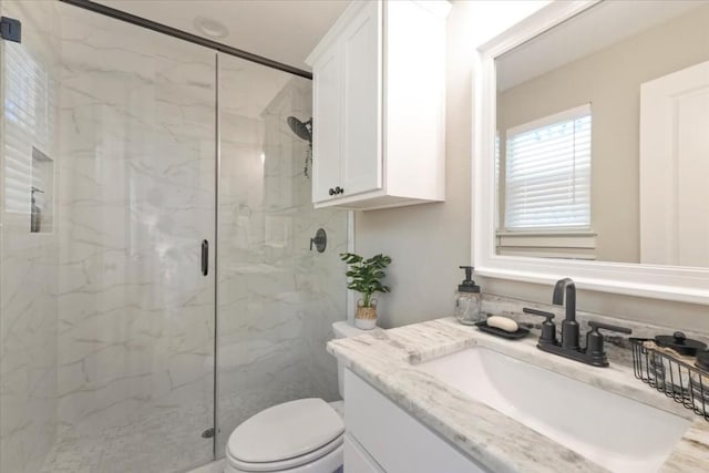 bathroom with a shower with door, vanity, and toilet