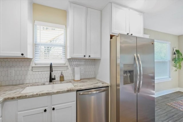 kitchen with white cabinetry, stainless steel appliances, light stone countertops, and sink