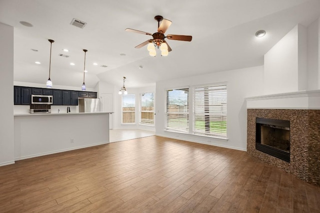 unfurnished living room featuring vaulted ceiling, a tile fireplace, dark hardwood / wood-style floors, and ceiling fan