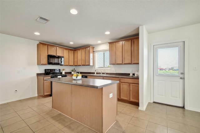 kitchen with sink, a center island, light tile patterned floors, and black appliances