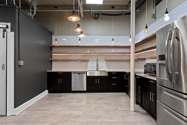 kitchen featuring sink, decorative light fixtures, appliances with stainless steel finishes, a towering ceiling, and backsplash