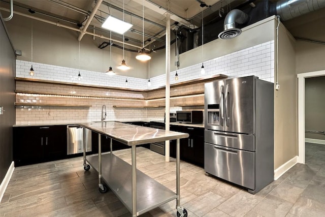 kitchen featuring sink, light wood-type flooring, stainless steel appliances, a high ceiling, and backsplash