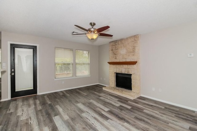 unfurnished living room featuring a fireplace, a textured ceiling, dark hardwood / wood-style floors, and ceiling fan