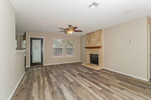 6333 La Mesa St, Leander, TX 78645 - unfurnished living room with a ceiling fan, wood finished floors, and a stone fireplace