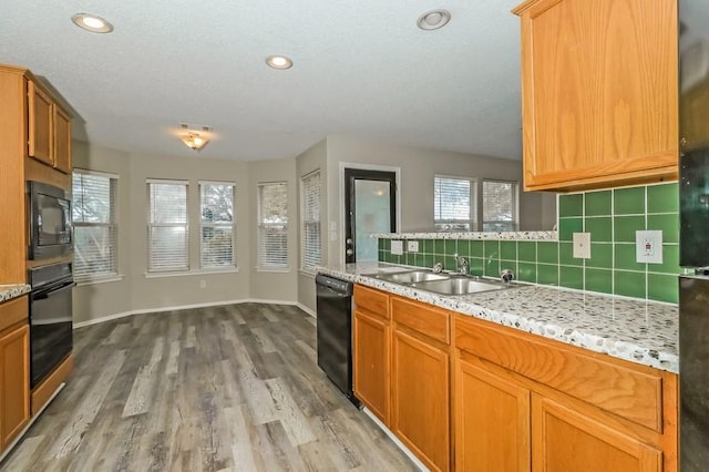 6333 La Mesa St, Leander, TX 78645 - kitchen with black appliances, backsplash, wood finished floors, light stone countertops, and recessed lighting