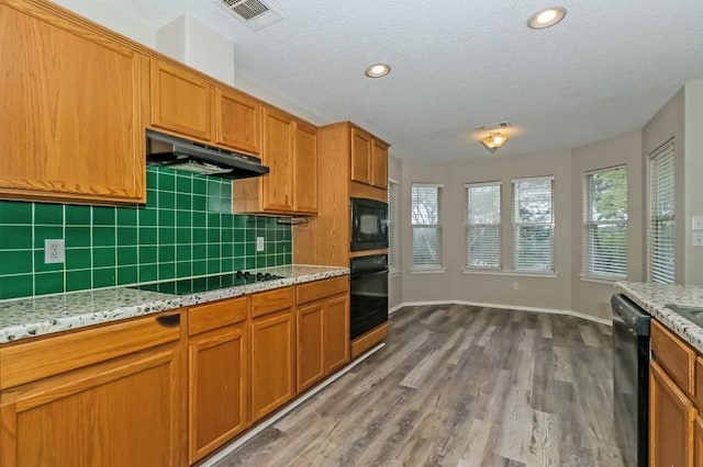 6333 La Mesa St, Leander, TX 78645 - kitchen featuring black appliances, under cabinet range hood, backsplash, dark wood-type flooring, and brown cabinets