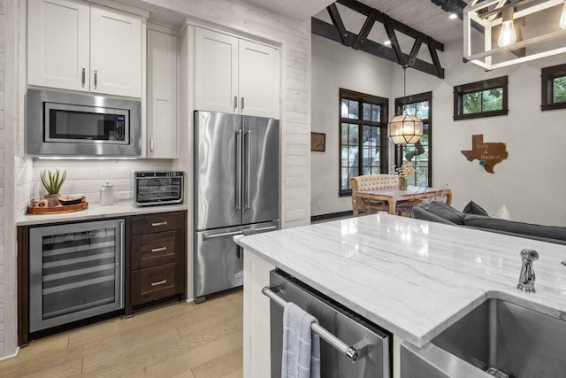 kitchen with sink, light hardwood / wood-style flooring, white cabinetry, stainless steel appliances, and beverage cooler