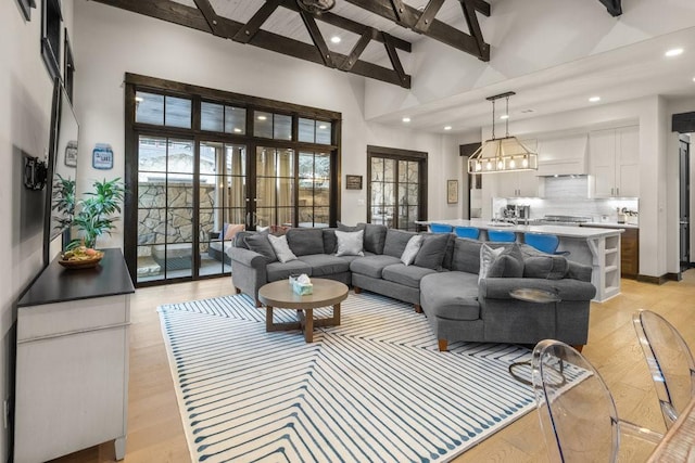 living room with light hardwood / wood-style flooring, high vaulted ceiling, french doors, and beamed ceiling