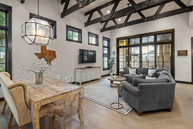 living room with high vaulted ceiling, light wood-type flooring, a healthy amount of sunlight, beam ceiling, and french doors