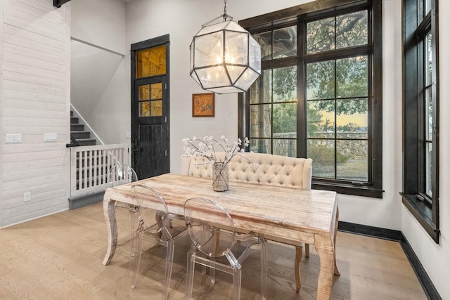 dining space with an inviting chandelier, wooden walls, and light hardwood / wood-style flooring