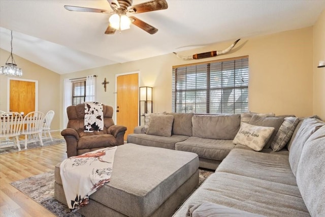 living room with ceiling fan with notable chandelier, lofted ceiling, and hardwood / wood-style floors