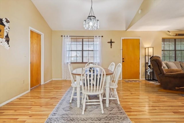 dining space with an inviting chandelier, vaulted ceiling, and light hardwood / wood-style flooring