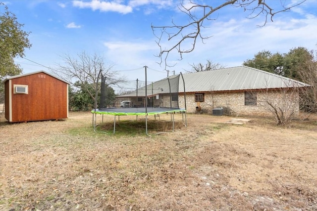 view of yard featuring a trampoline, cooling unit, and a shed