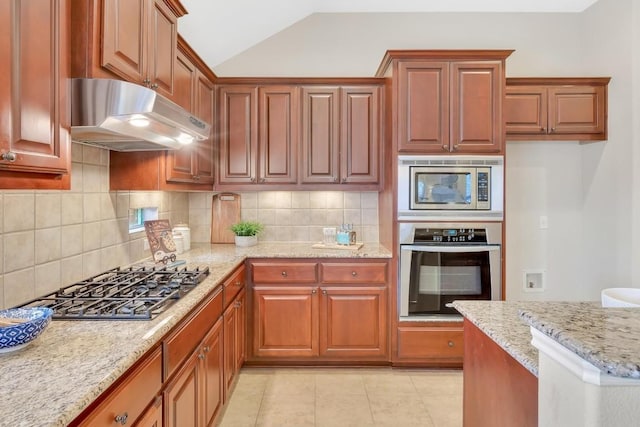 kitchen featuring vaulted ceiling, light tile patterned floors, stainless steel appliances, light stone countertops, and backsplash