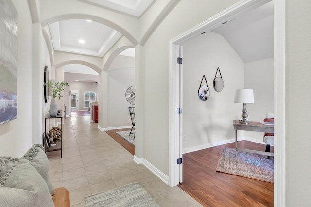 corridor with light tile patterned floors and a tray ceiling