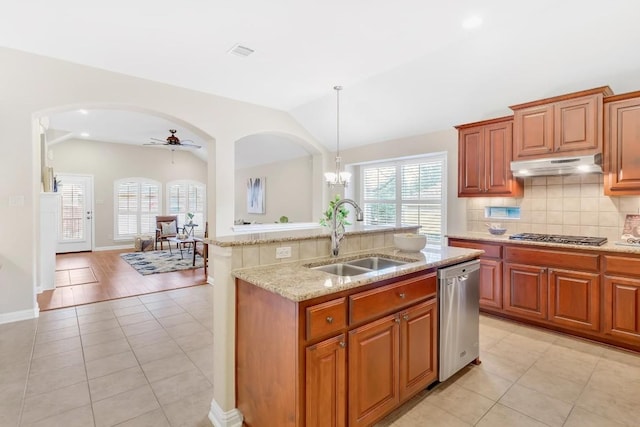 kitchen with vaulted ceiling, appliances with stainless steel finishes, an island with sink, sink, and hanging light fixtures