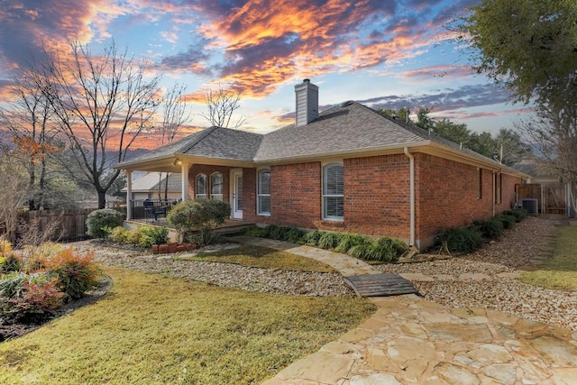 view of front of property featuring cooling unit, a patio area, and a lawn