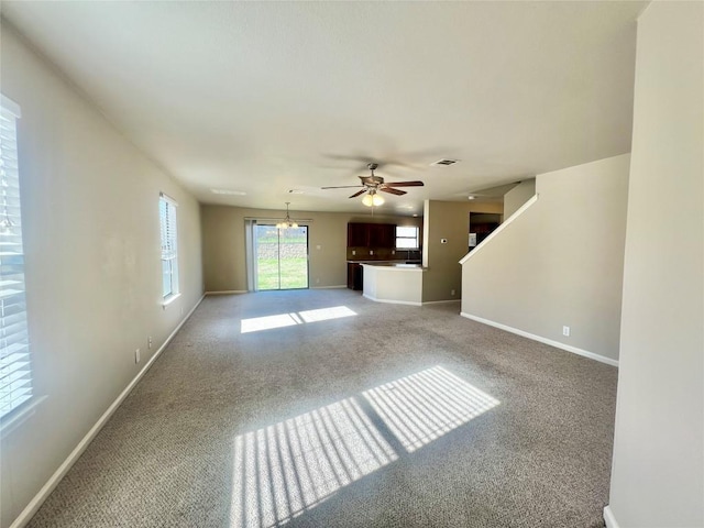 unfurnished living room with carpet floors and ceiling fan with notable chandelier