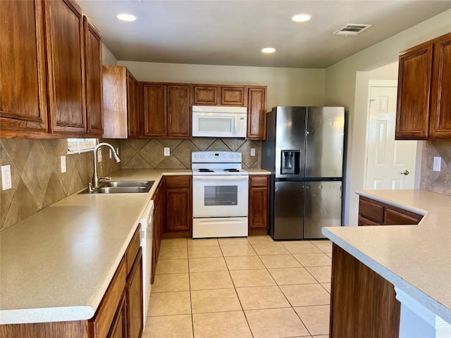 kitchen with sink, light tile patterned floors, backsplash, and white appliances