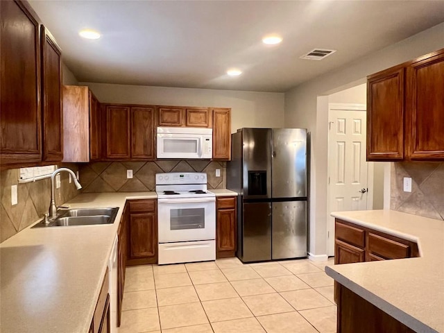 kitchen featuring sink, light tile patterned floors, white appliances, and decorative backsplash