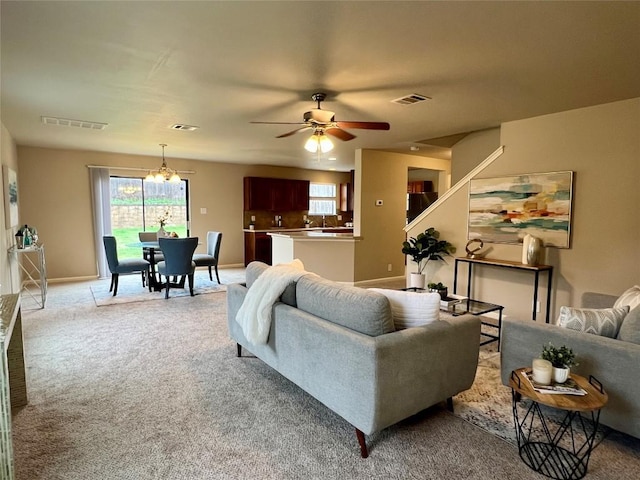 living room with light carpet and ceiling fan with notable chandelier