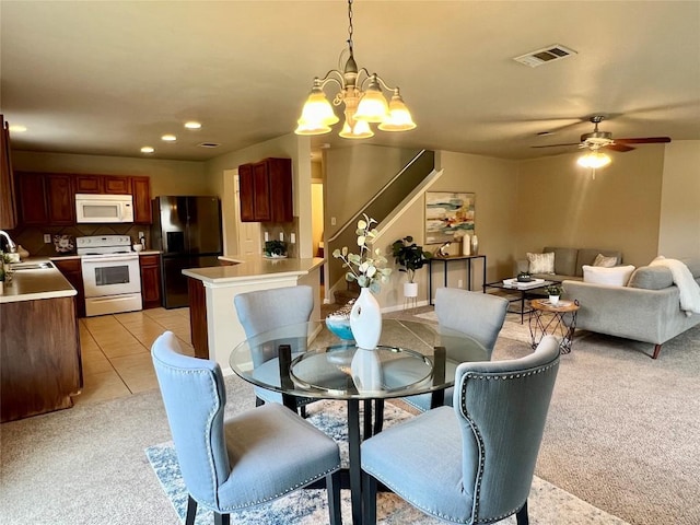 tiled dining space featuring sink and ceiling fan with notable chandelier