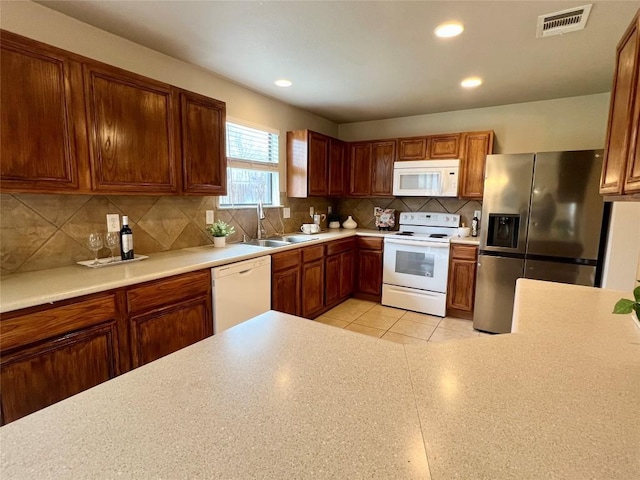 kitchen featuring sink, light tile patterned floors, backsplash, and white appliances