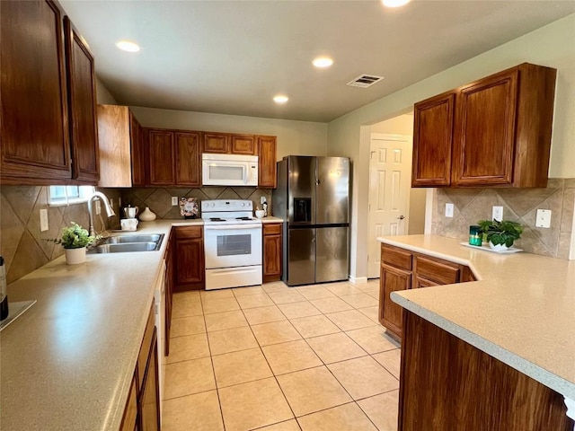 kitchen featuring sink, light tile patterned floors, backsplash, and white appliances