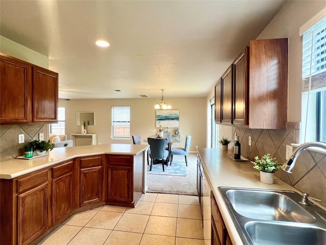 kitchen with pendant lighting, sink, light tile patterned floors, and tasteful backsplash