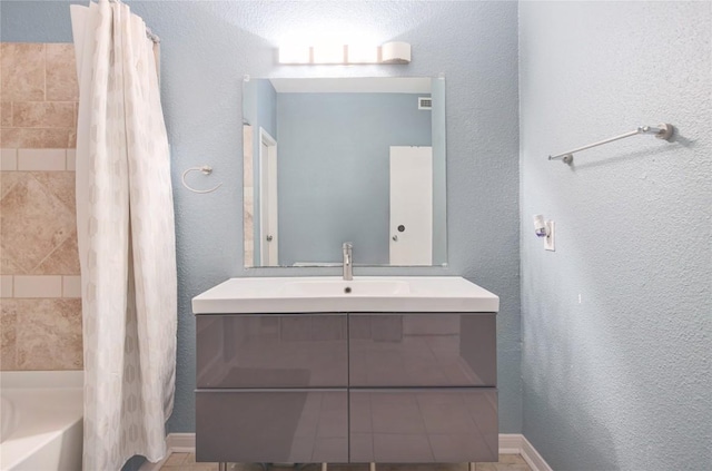 2450 Wickersham Ln Unit M1311, Austin, TX 78741 - bathroom featuring vanity, shower / bath combo with shower curtain, a textured wall, and baseboards