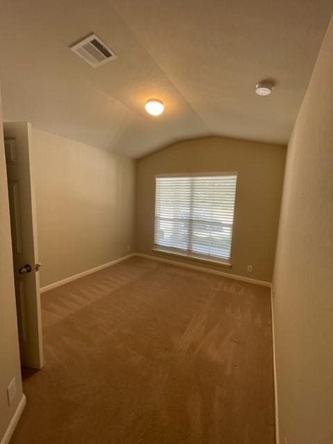 carpeted empty room featuring vaulted ceiling