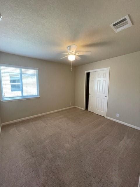 unfurnished bedroom with ceiling fan, carpet floors, a closet, and a textured ceiling