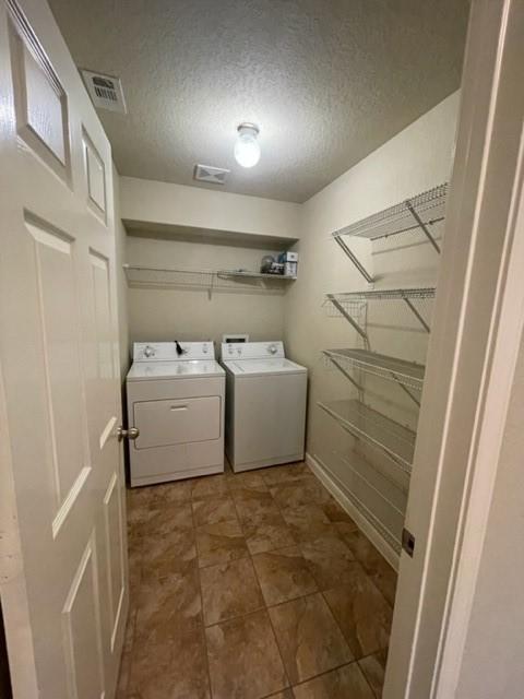 laundry room with washing machine and clothes dryer and a textured ceiling