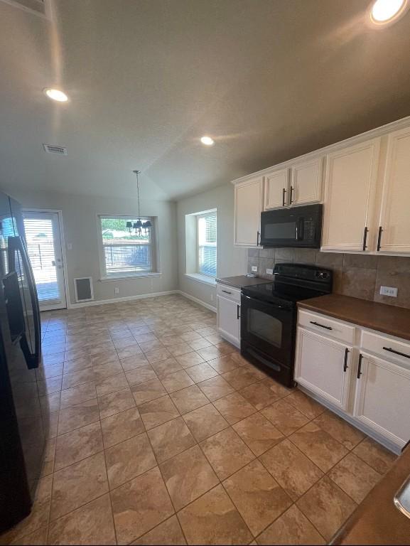 kitchen featuring light tile patterned flooring, white cabinetry, tasteful backsplash, decorative light fixtures, and black appliances