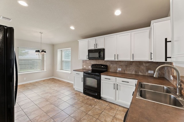 kitchen with dark countertops, visible vents, a sink, and black appliances