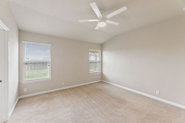 spare room with lofted ceiling, baseboards, a ceiling fan, and light colored carpet