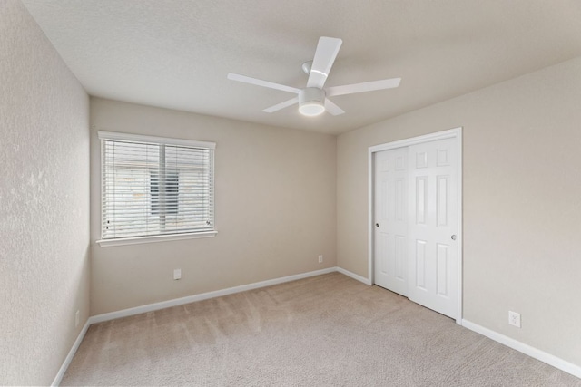 unfurnished bedroom with carpet floors, a closet, ceiling fan, and baseboards